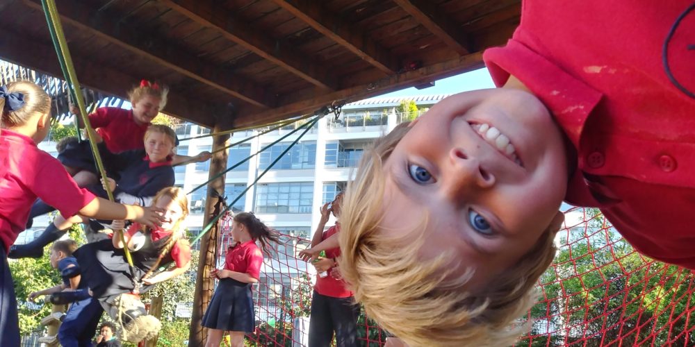 boy hanging upside-down from climbing frame