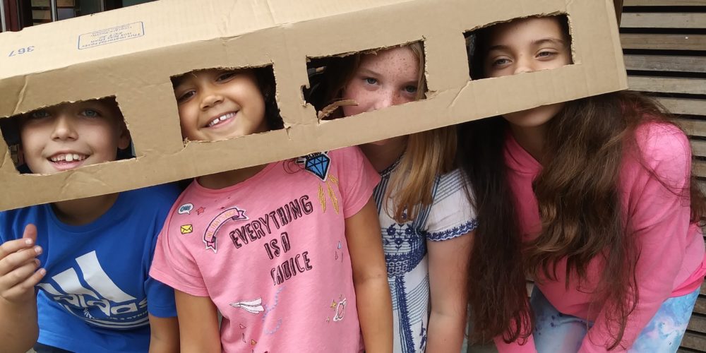 Four children with cut out cardboard boxes on them