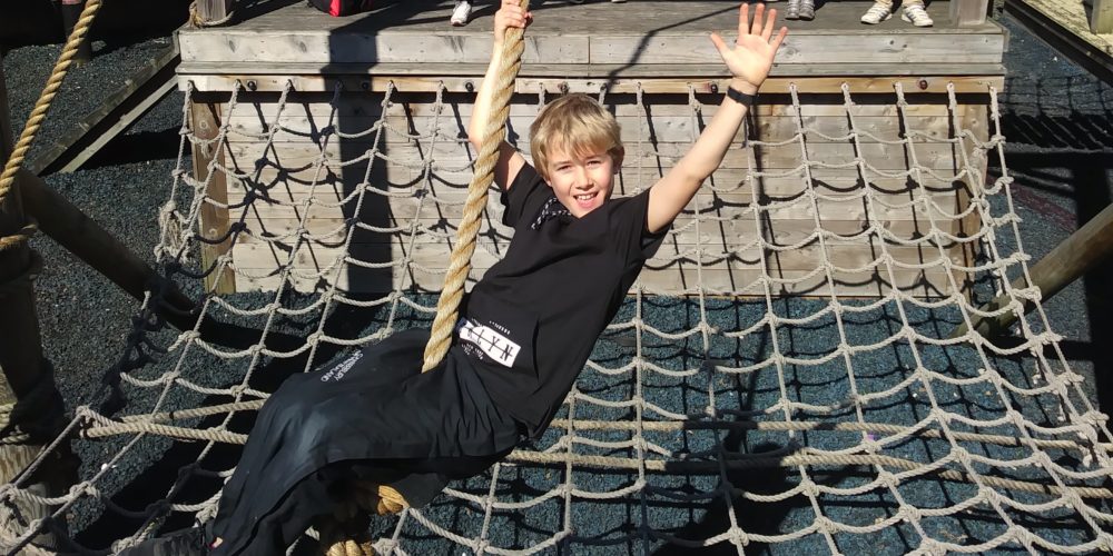 Boy on rope swing waving